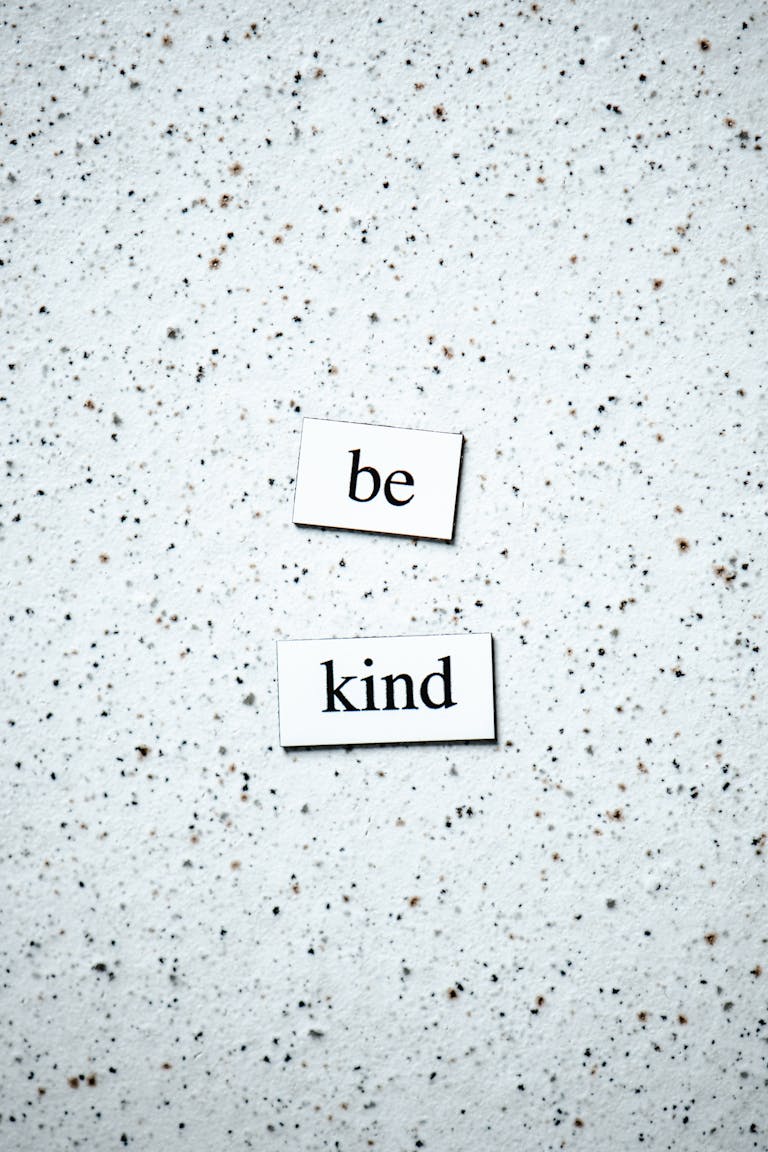 Inspirational 'Be Kind' message on a neutral speckled background, perfect for motivational themes.