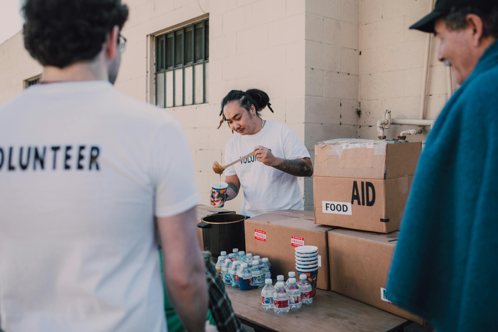 Volunteers serve food and water at an outdoor aid station, promoting generosity and helping communities.